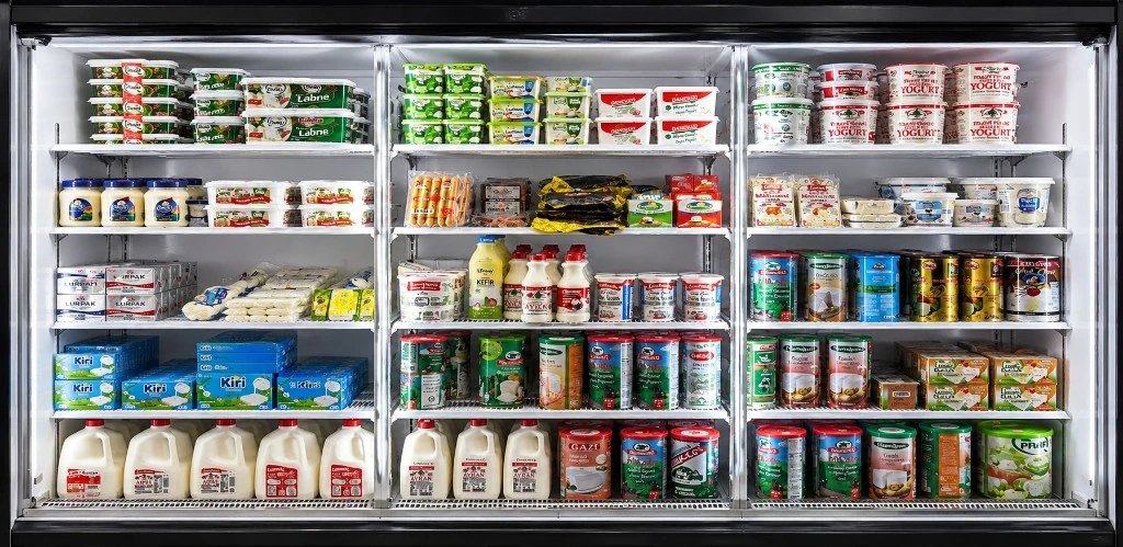 Reach-in dairy cooler stocked with milk, yogurt, cheese, and refrigerated dairy products