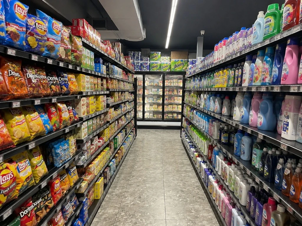 Store aisle with snacks and chips on one side and laundry detergents and household cleaners on the other